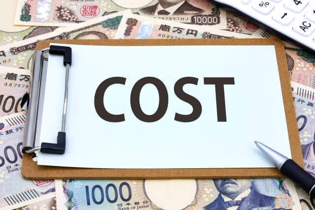 「COST」と印字されたA４用紙をバインダーで挟んでいる。その周りには大量の紙幣